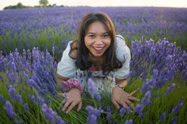 Açık havada, beyaz yaz elbiseli, mutlu ve çekici bir kadının romantik portresi seyahat ve tatil konseptindeki lavanta çiçekleri tarlasında tasasız eğleniyor.