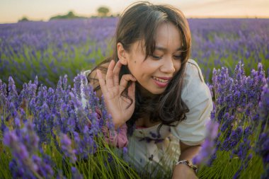Açık havada, beyaz yaz elbiseli, mutlu ve çekici bir kadının romantik portresi seyahat ve tatil konseptindeki lavanta çiçekleri tarlasında tasasız eğleniyor.