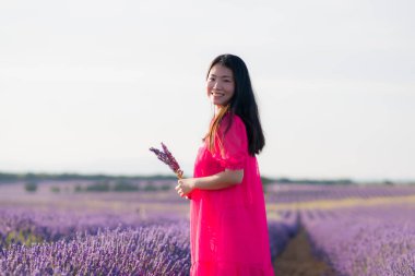 Lavanta çiçekleri tarlasında genç Asyalı bir kadın. Mutlu ve güzel bir Japon kızı. Tatlı, mavi yaz elbisesi içinde.