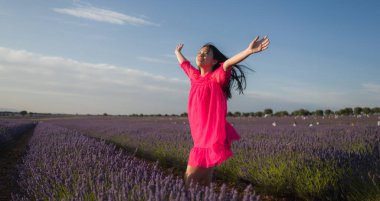Lavanta çiçekleri tarlasında genç Asyalı bir kadın. Mutlu ve güzel bir Japon kızı. Tatlı, mavi yaz elbisesi içinde.