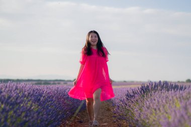 Lavanta çiçekleri tarlasında genç Asyalı bir kadın. Mutlu ve güzel bir Japon kızı. Tatlı, mavi yaz elbisesi içinde.