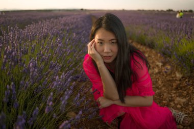Lavanta çiçekleri tarlasında genç Asyalı bir kadın. Mutlu ve güzel bir Japon kızı. Tatlı, mavi yaz elbisesi içinde.