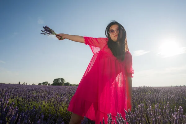 Genç Asyalı kadın lavanta çiçekleri tarlasında mutlu ve güzel bir Çinli kız tatlı mavi elbisesiyle tatilin tadını çıkarıyor mor çiçekli çayırlarda dinleniyor.