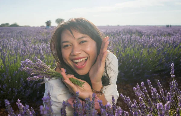 Açık havada, beyaz yaz elbiseli, mutlu ve çekici bir kadının romantik portresi seyahat ve tatil konseptindeki lavanta çiçekleri tarlasında tasasız eğleniyor.
