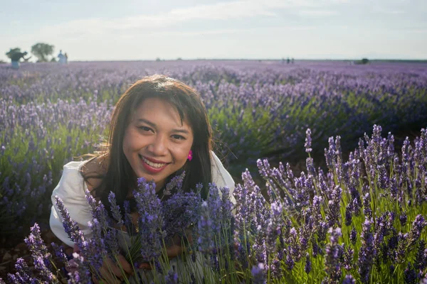 Açık havada, beyaz yaz elbiseli, mutlu ve çekici bir kadının romantik portresi seyahat ve tatil konseptindeki lavanta çiçekleri tarlasında tasasız eğleniyor.