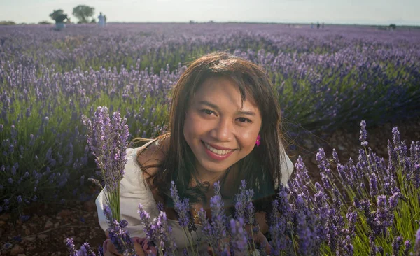 Açık havada, beyaz yaz elbiseli, mutlu ve çekici bir kadının romantik portresi seyahat ve tatil konseptindeki lavanta çiçekleri tarlasında tasasız eğleniyor.