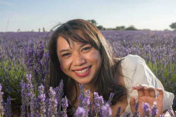 Açık havada, beyaz yaz elbiseli, mutlu ve çekici bir kadının romantik portresi seyahat ve tatil konseptindeki lavanta çiçekleri tarlasında tasasız eğleniyor.