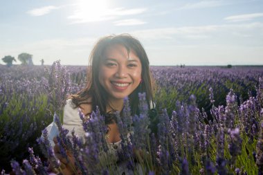 Açık havada, beyaz yaz elbiseli, mutlu ve çekici bir kadının romantik portresi seyahat ve tatil konseptindeki lavanta çiçekleri tarlasında tasasız eğleniyor.