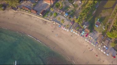 Endonezya 'nın Bali adasındaki temiz ve güzel cennet kumsalının insansız hava aracı görüntüsü hala denizin üzerinde asılı duruyor. Kumda güneş şemsiyeleri var.