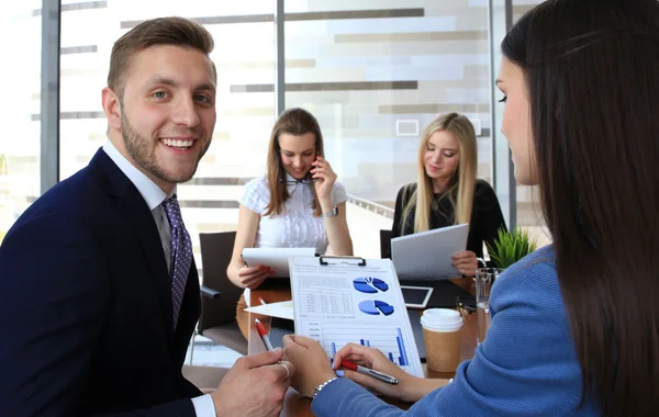 Felice uomo d'affari intelligente con i compagni di squadra discutendo in background — Foto Stock