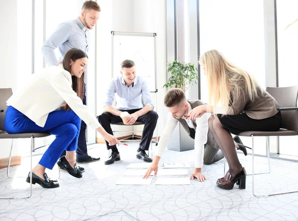 Personas creativas mirando el plan de proyecto presentado en el piso —  Fotos de Stock