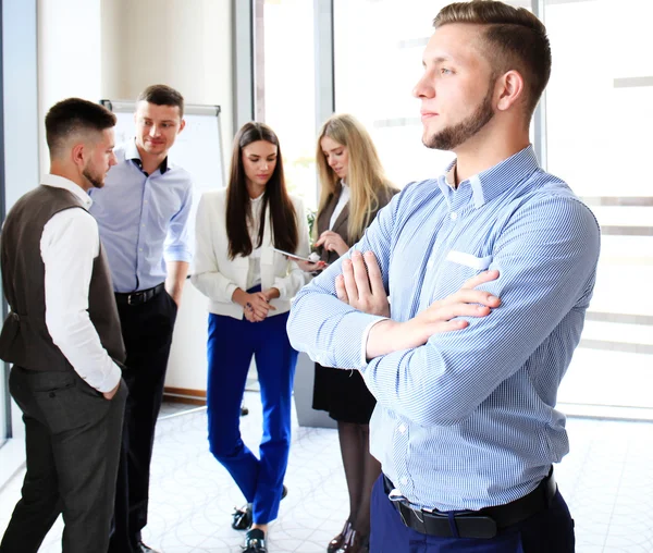 Feliz hombre de negocios inteligente con compañeros de equipo discutiendo en el fondo — Foto de Stock