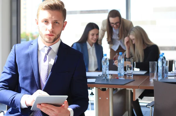 Glad smart affärsman med lagkamrater diskuterar i bakgrunden — Stockfoto