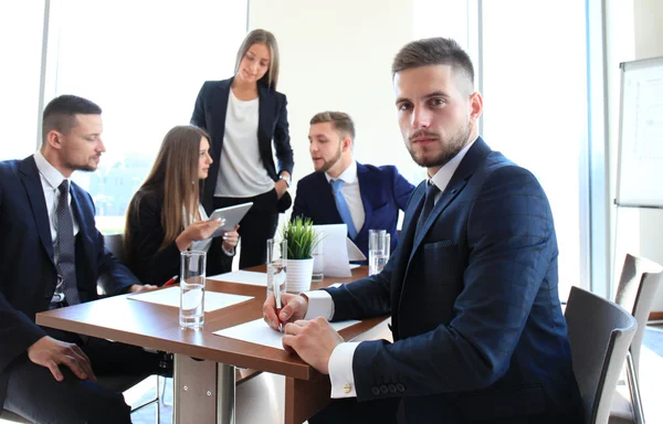 Empresário com colegas em segundo plano no cargo — Fotografia de Stock