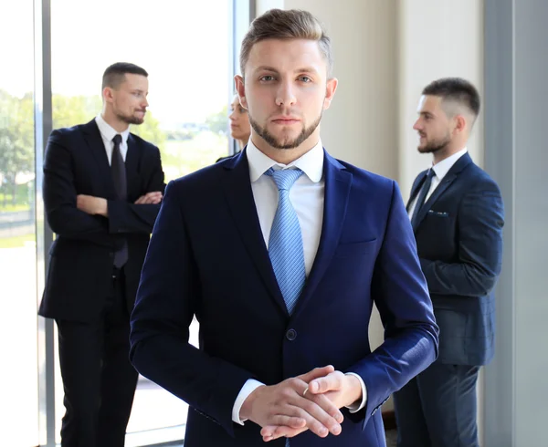 Jonge zakenman permanent op kantoor met zijn collega op de achtergrond — Stockfoto