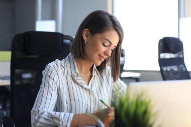 Güzel iş kadını büro masasında otururken bir şeyler yazıyor..