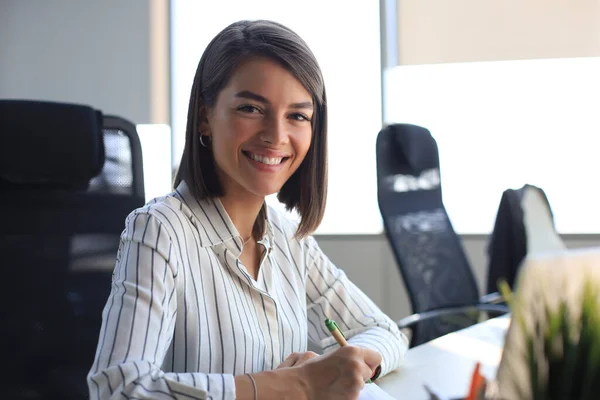 Mooie Zakenvrouw Iets Aan Het Opschrijven Terwijl Het Bureau Zit — Stockfoto