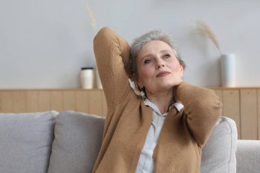 Çekici orta yaşlı kadın evdeki kanepede dinleniyor.