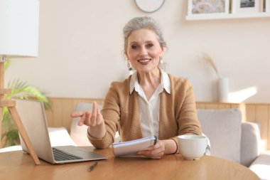 Gülümseyen orta yaşlı güzel bir kadının portresi. Kameraya bakıyor, video görüşmesi yapıyor, iş görüşmesi yapıyor ya da internetten biriyle çıkıyor.