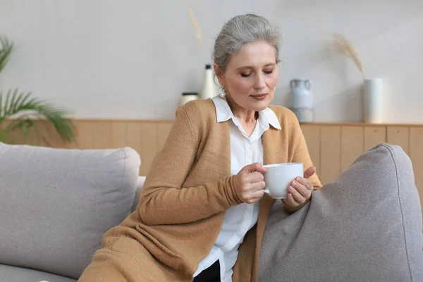 Счастливая Зрелая Женщина Отдыхает Удобном Диване Пить Кофе Чай Глядя — стоковое фото