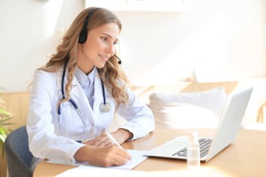 İnternette çalışan dost canlısı bir doktor danışma masasında oturuyor.