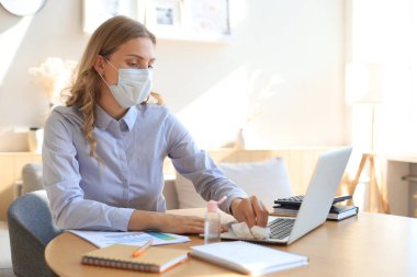 Kadın dezenfektan jel kullanıyor. Bilgisayarı dezenfektanla temizliyorum. Coronavirus koruması