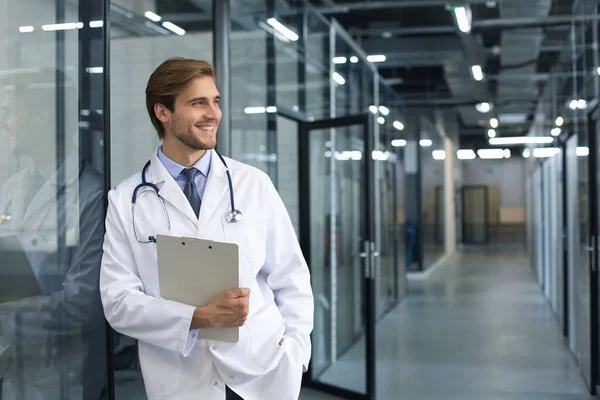 Portrait of doctor standing in hospital corridor wearing lab coat and stethoscope