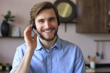 Kulaklıklı ve gülümseyen bir erkek müşteri destek operatörü.