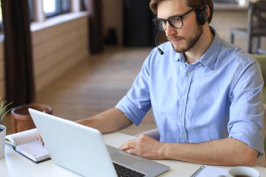 Serbest çalışan, kulaklıklarla konuşan ve merkez ofisteki müşterilere danışan biri.