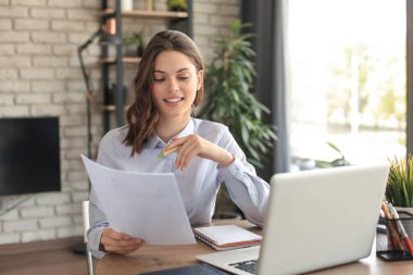 Mutlu girişimci kadın, masa başında oturup, post-paper yazışmalarında iyi haberler okuyor.