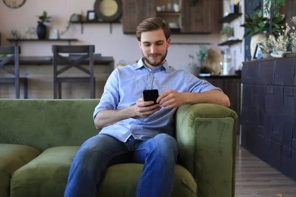 Attraktiv Ung Man Koppla Soffa Hemma Och Använda Mobiltelefon För — Stockfoto