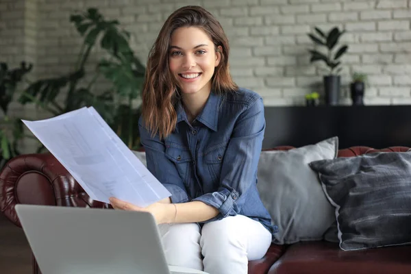 Business woman checking paper documents in home office,working on laptop from home