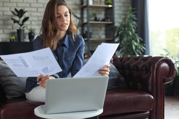 Business woman checking paper documents in home office,working on laptop from home