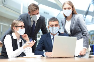 Epidemide koruyucu maskeler takan bir grup iş adamı ofiste kurumsal konsepti tartışıyor..