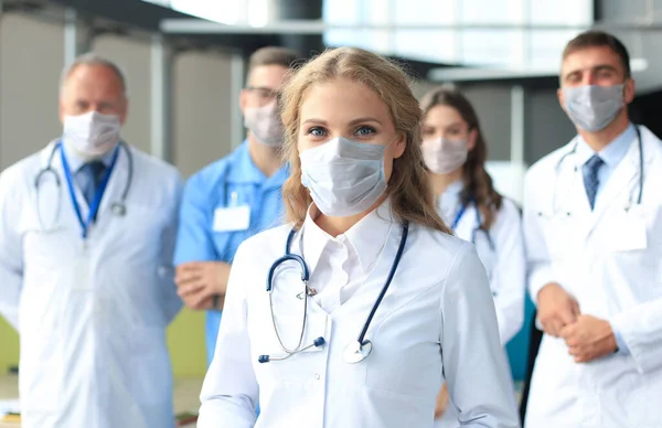 Žena lékař v lékařské masce se skupinou šťastně úspěšných kolegů i v preventivních maskách. — Stock fotografie