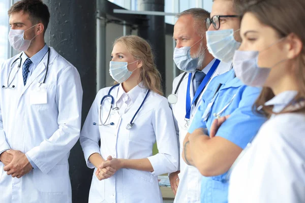 Tým různých lékařů, kteří nosí lékařské masky a konverzují v nemocnici. — Stock fotografie