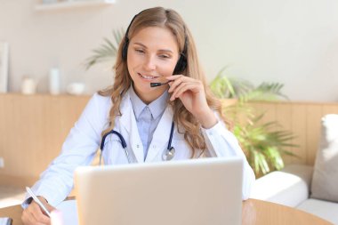 İnternette bilgisayarla çalışan konsantre bir doktor danışma masasında oturuyor.