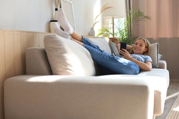 Hübsches Mädchen Mit Ihrem Smartphone Auf Der Heimischen Couch Wohnzimmer — Stockfoto