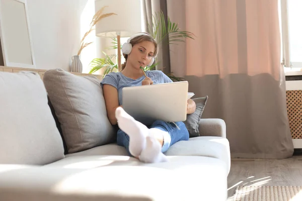 Lächelnde Junge Frau Mit Kopfhörer Und Laptop Auf Dem Sofa — Stockfoto