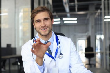 Gülümseyen yakışıklı erkek doktor hastayla kameraya konuşuyor.