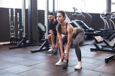 Formda ve kaslı bir çift spor salonunda egzersiz yaparken dambıl kaldırmaya odaklanmış.