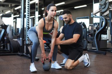 Spor salonunda müşterisiyle egzersiz yapan beden eğitimi öğretmeni.