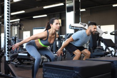 Uygun spor salonunda çömelme hareketleri yapan zinde bir çift.