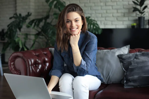 Χαμογελαστή Νεαρή Γυναίκα Που Κάθεται Στον Καναπέ Φορητό Υπολογιστή Και — Φωτογραφία Αρχείου