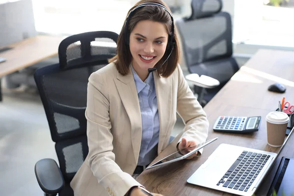 사무실 책상에 앉아서 디지털 기기에 연결을 사용하여 업무를 수행하는 관리자 — 스톡 사진