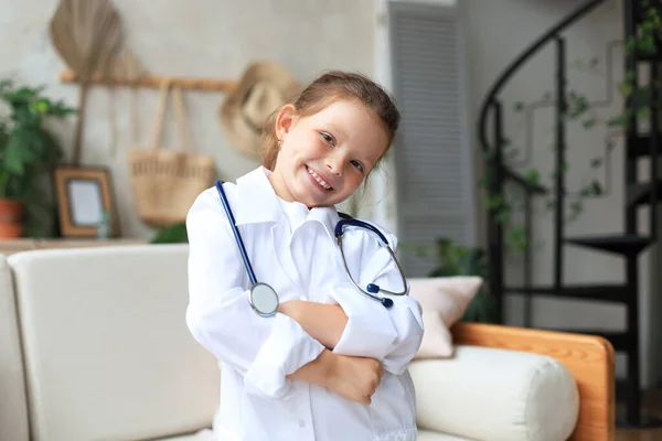 Улыбающаяся Маленькая Девочка Медицинской Форме Играет Стетоскопом Дома — стоковое фото