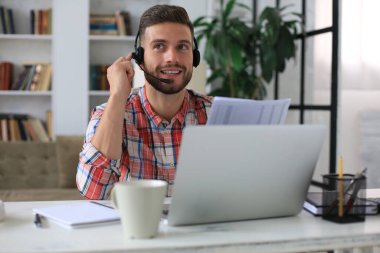 Konsantre genç serbest çalışan işadamı video konferansı için dizüstü bilgisayar kullanıyor, evde uzaktan çalışıyor.