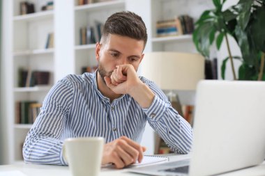 Yoğunlaşmış modern iş adamı ofiste çalışırken laptop kullanarak veri analiz ediyor.