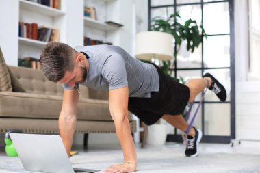 Karantina sırasında evde tahta egzersizi yapan çekici bir adam. Fitness sağlığın anahtarıdır