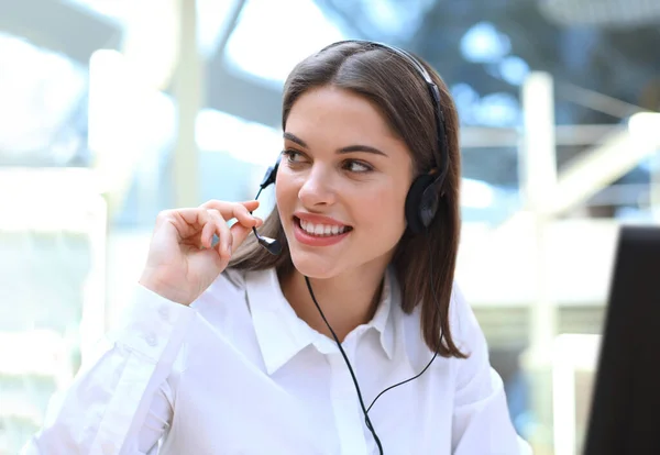 Όμορφη νεαρή γυναίκα τηλεφωνήτρια κέντρο με ακουστικά στο γραφείο. — Φωτογραφία Αρχείου